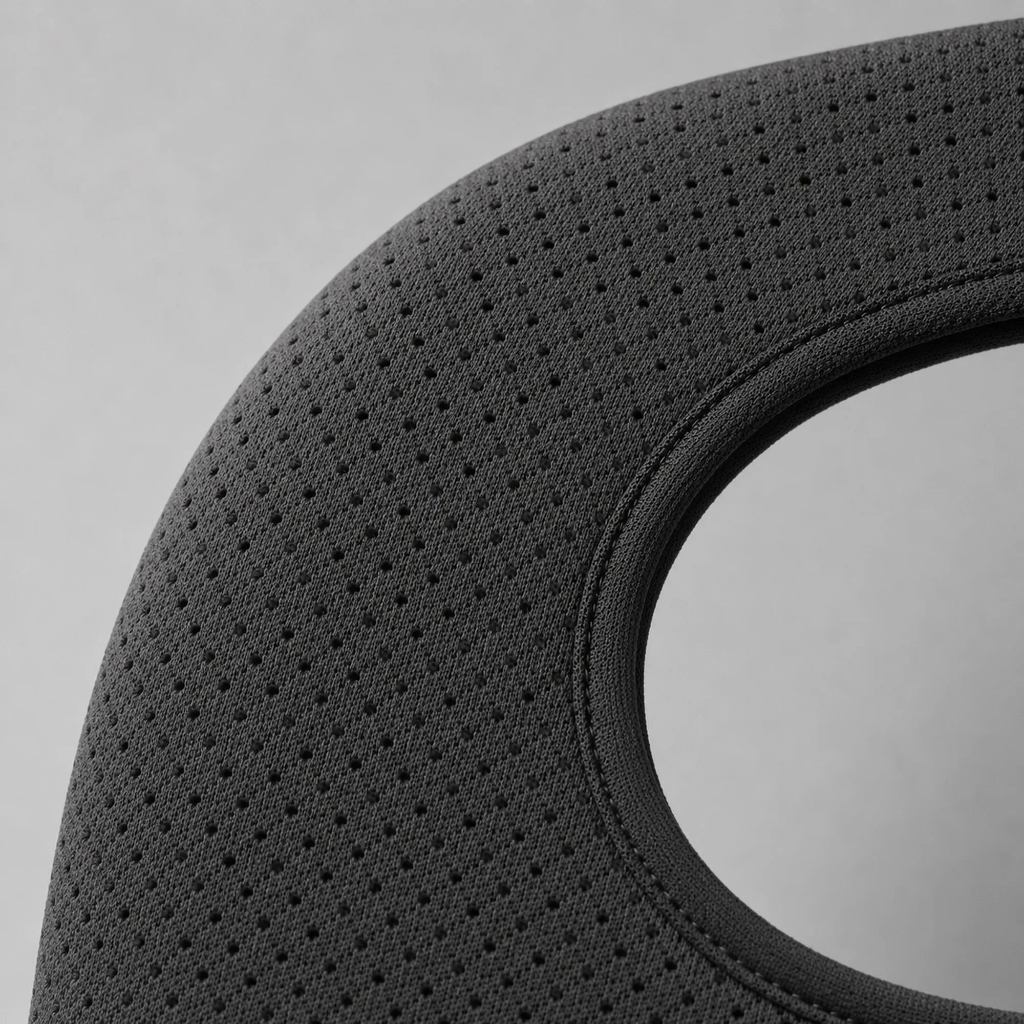 Close-up of the shoulder brace's perforated breathable strap fabric, showing the mesh weave and stitched seam